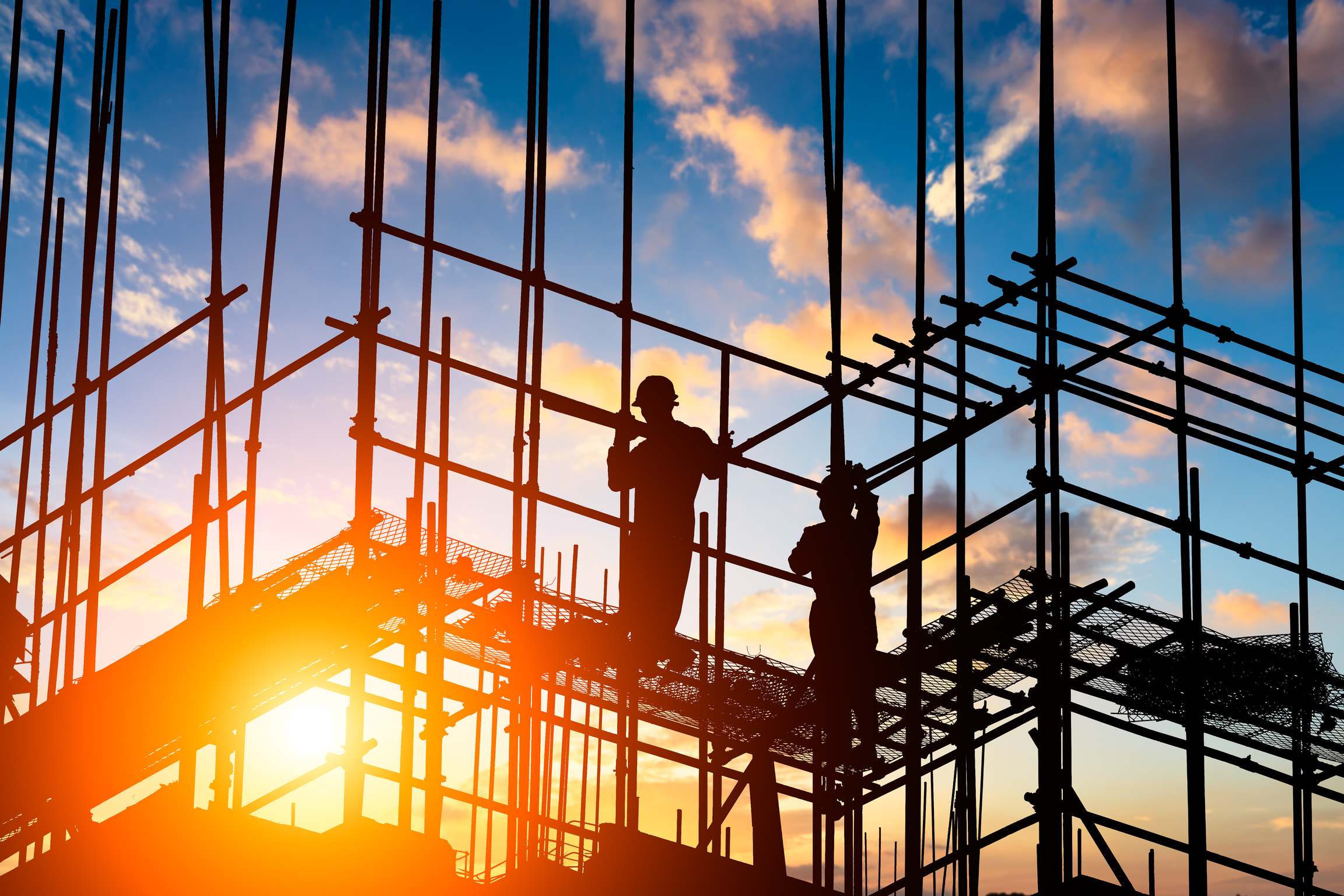 Construction workers on scaffolding at sunset